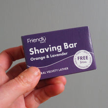 Load image into Gallery viewer, Hand holding a purple 'Friendly' shaving bar packaging against a gray background