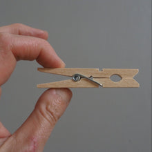 Load image into Gallery viewer, Hand holding a wooden clothespin against a gray background