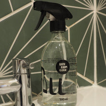 Load image into Gallery viewer, A 500ml clear spray bottle of All in Use Bath Room Cleaner with a black trigger sprayer, placed on a white ceramic sink next to a chrome faucet in front of a green geometric tiled wall.