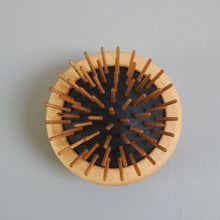 Load image into Gallery viewer, Round wooden coaster with central black circle on a light gray background