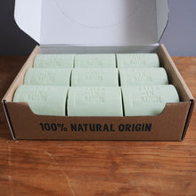 Load image into Gallery viewer, Box of green bars of soap with '100% Natural Origin' text on a wooden surface.
