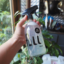 Load image into Gallery viewer, A hand holding a 500ml spray bottle of FILL All Purpose cleaning spray, with a kitchen background and green plants visible.
