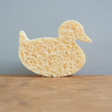 Load image into Gallery viewer, Sponge shaped like a duck on a wooden surface with a gray background