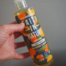 Load image into Gallery viewer, Hand holding a bottle of 'In Nature' product with a colorful label against a gray background