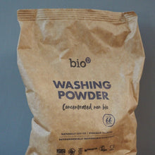 Load image into Gallery viewer, A brown paper bag of bio Washing Powder Concentrated non bio, standing on a wooden surface against a blue-gray wall.