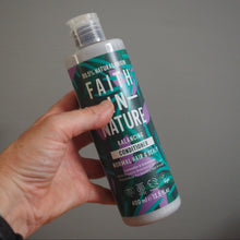 Load image into Gallery viewer, Hand holding a bottle of Faith in Nature conditioner against a gray background