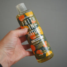 Load image into Gallery viewer, Hand holding a bottle of Faith in Nature Purifying Shampoo against a gray background