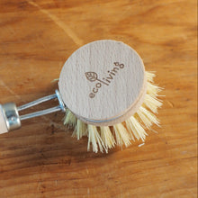 Load image into Gallery viewer, A small hand brush with a light wood handle and round wooden head, shown on a wooden surface. The wooden head is engraved with the brand name 'eco living'.