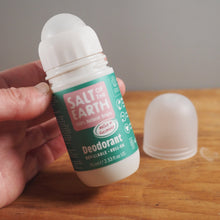 Load image into Gallery viewer, A hand holds a roll-on deodorant bottle labeled 'Salt the Earth' next to its cap on a wooden tabletop.