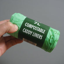 Load image into Gallery viewer, Green roll of compostable caddy liners held by a hand against a gray background
