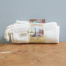 Load image into Gallery viewer, Rolled-up towel with packaging on a wooden surface against a gray wall
