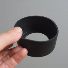Load image into Gallery viewer, Hand holding a black silicon ring against a grey background
