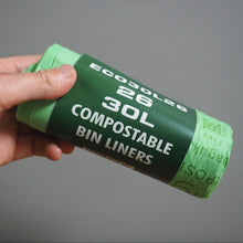 Load image into Gallery viewer, Hand holding a roll of eco30lze compostable bin liners against a gray background
