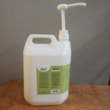 Load image into Gallery viewer, A large white plastic dispenser bottle with a pump, shown lying on its side on a wooden surface against a gray background.
