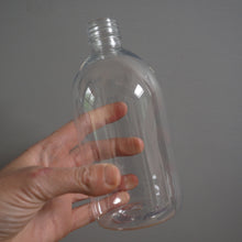 Load image into Gallery viewer, Clear plastic bottle held by a hand against a gray background
