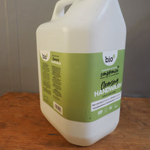 Load image into Gallery viewer, A large white plastic jug of 'bjo' bio compound hand cleaner with a green label, resting on a wooden surface against a gray wall.
