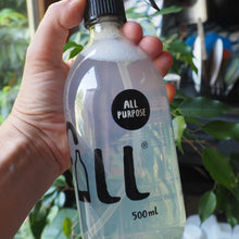 Load image into Gallery viewer, A hand holding a clear plastic spray bottle with a black trigger sprayer. The bottle has a black circular label that reads 'ALL PURPOSE' and '500ml' printed on it.
