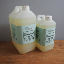 Load image into Gallery viewer, Two large plastic containers of laundry liquid on a wooden surface.
