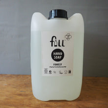 Load image into Gallery viewer, A large translucent white plastic jerrycan of Full Hand Soap in the Forest scent, sitting on a wooden tabletop with a gray backdrop.
