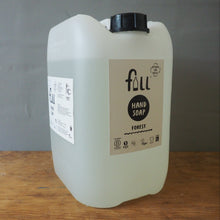 Load image into Gallery viewer, A large translucent white plastic jerrycan of full forest hand soap with a black cap, sitting on a wooden table against a gray background.
