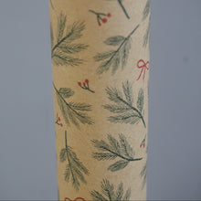Load image into Gallery viewer, A close-up of a cylindrical tube or roll wrapped in beige kraft paper with a repeating pattern of green pine branches, small red berries, and red bows, set against a solid gray background.
