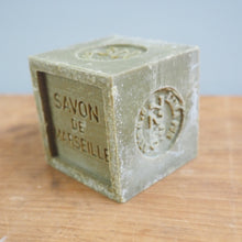 Load image into Gallery viewer, Block of Savon de Marseille soap on a wooden surface with a light blue background
