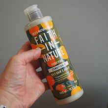Load image into Gallery viewer, Hand holding a bottle labeled 'Faith in Nature' against a gray background

