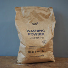 Load image into Gallery viewer, A brown paper bag of bio Washing Powder standing on a wooden surface against a blue-gray wall.
