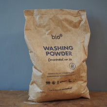 Load image into Gallery viewer, A brown paper bag of bio Washing Powder standing on a wooden surface against a blue-gray wall.
