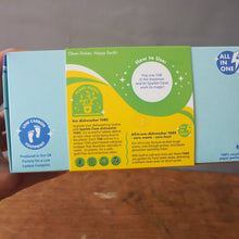 Load image into Gallery viewer, A hand holding a light blue and green product box with yellow and white panels, showing printed instructions and branding for a foot care product. The box is photographed against a neutral gray wall and wooden floor background.
