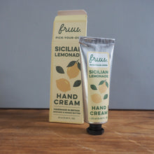 Load image into Gallery viewer, A squeeze tube and matching box of fru. Sicilian Lemonade Hand Cream placed on a wooden surface against a plain gray wall.
