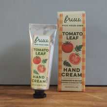 Load image into Gallery viewer, A tube and box of Pruitt Hand Cream with Tomato Leaf scent, standing on a wooden surface against a gray wall.
