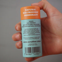 Load image into Gallery viewer, A hand holding a deodorant stick with a light blue body and an orange cap. The label reads 'NATURAL ECO FRIENDLY DEODORANT' and shows the website www.
